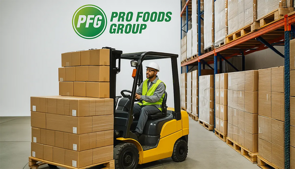Forklift moving a pallet of boxes in a Pro Foods Group warehouse, with subtle PFG branding on select packaging and organized shelves in the background, symbolizing scalability, trust, and professional turnkey solutions.