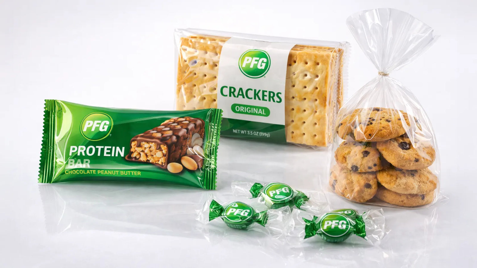Assortment of PFG snack products wrapped in high-gloss BOPP film including protein bar, crackers, candies, and clear bakery packaging showing tight seals and premium finish