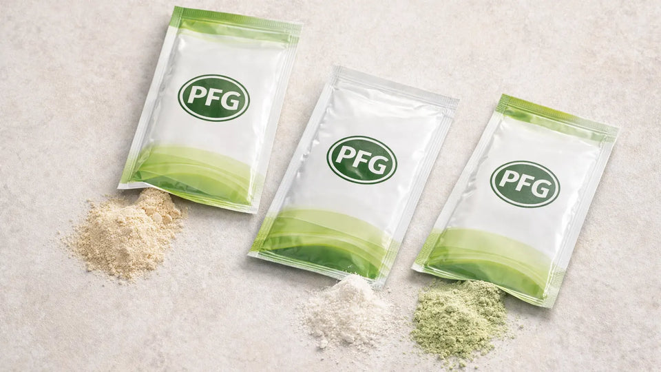 Several sachets arranged on a clean surface with small amounts of powder visible, representing portion-controlled packaging for beverage mixes, seasonings, and nutritional products with subtle PFG branding